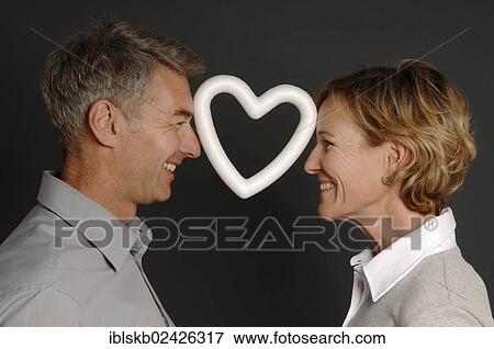 Stock Photo - "Couple, 35-45, standing face to face and holding a styrofoam heart between their foreheads". Fotosearch