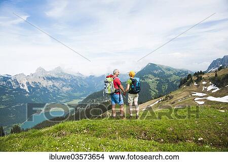 Picture - "Couple enjoying the view of Lake Haldensee, Neunerkopfle, Tannheim Valley, Tyrol, Austria, Europe". Fotosearch