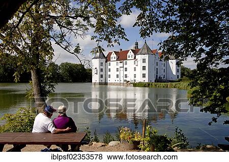 Stock Photo - "Couple on a bench in front of Schloss Gluecksburg Castle, a Renaissance castle in Gluecksburg on the Flensburg Fjord, Schleswig-Holstein, Germany, Europe". Fotosearch