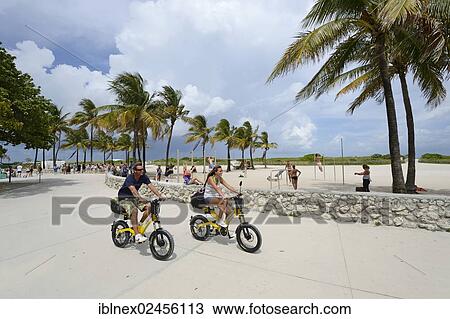 "Couple riding electric bicycles, Ocean Drive, South Beach, Miami, Florida, USA" View Large Photo Image Stock Image - "Couple riding electric bicycles, Ocean Drive, South Beach, Miami, Florida, USA". Fotosearch