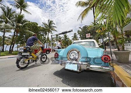 Stock Photo - "Couple riding electric bicycles, Ocean Drive, South Beach, Miami, Florida, USA". Fotosearch