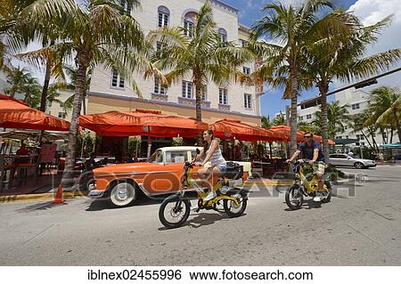 Stock Photograph - "Couple riding electric bicycles, Ocean Drive, South Beach, Miami, Florida, USA". Fotosearch