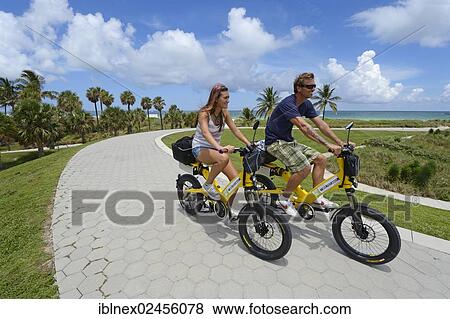 Stock Photo - "Couple riding electric bicycles, South Pointe Park, South Beach, Miami, Florida, USA". Fotosearch