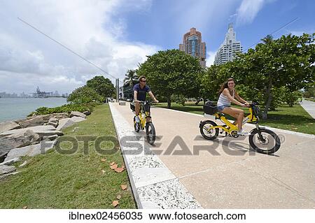 Stock Photography - "Couple riding electric bicycles, South Pointe Park, South Beach, Miami, Florida, USA". Fotosearch