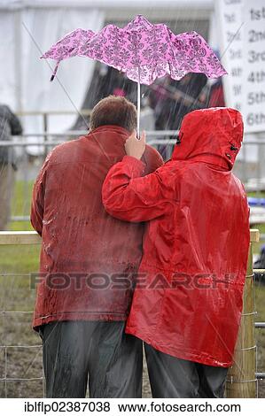 "Couple sheltering under small umbrella during thunderstorm at agricultural show, Royal Highland Show, Edinburgh, Scotland, United Kingdom, Europe" View Large Photo Image Stock Photo - "Couple sheltering under small umbrella during thunderstorm at agricultural show, Royal Highland Show, Edinburgh, Scotland, United Kingdom, Europe". Fotosearch