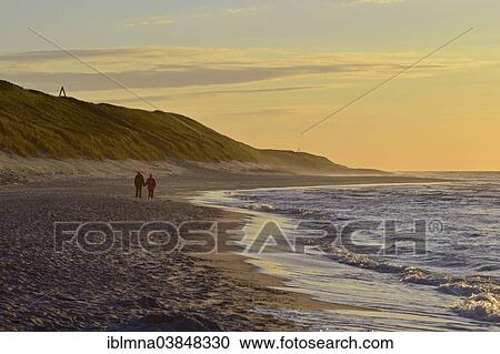 Stock Image - "Couple strolling along the sea shore, Wangerooge, Friesland, Lower Saxony, Germany, Europe". Fotosearch