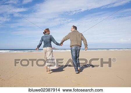 Couple walking along a beach View Large Photo Image Picture - Couple walking along a beach. Fotosearch