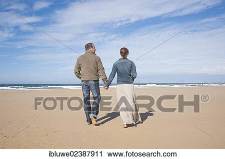 Couple walking along a beach View Large Photo Image Stock Image - Couple walking along a beach. Fotosearch