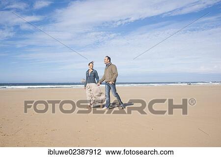 Couple walking along a beach View Large Photo Image Stock Image - Couple walking along a beach. Fotosearch