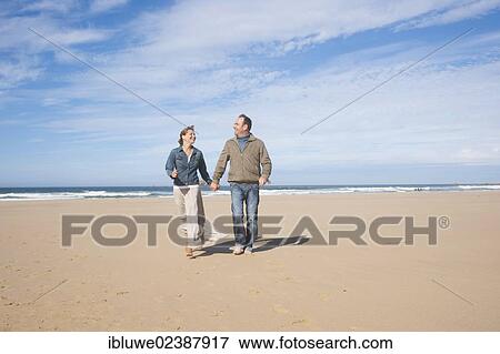 Couple walking along a beach View Large Photo Image Stock Photo - Couple walking along a beach. Fotosearch