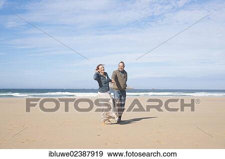 Couple walking along the beach View Large Photo Image Stock Photo - Couple walking along the beach. Fotosearch