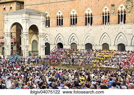 Stock Image - "Crowds in front of the Palazzo Publico on a training day of the historical horse race Palio di Siena, Piazza del Campo, Siena, Tuscany, Italy, Europe". Fotosearch