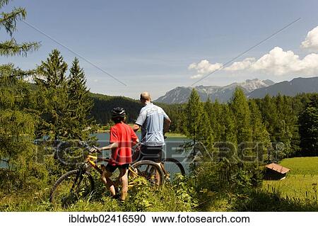 Cycling tour with mountain bikes, father and son in front of Lake Lautersee, Mittenwald, Karwendel Mountains, Werdenfelser Land, Upper Bavaria, Bavaria, Germany, Europe View Large Photo Image Stock Image - Cycling tour with mountain bikes, father and son in front of Lake Lautersee, Mittenwald, Karwendel Mountains, Werdenfelser Land, Upper Bavaria, Bavaria, Germany, Europe. Fotosearch