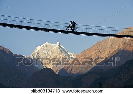 "Cyclist crossing a suspension Bridge over Kali Ghandaki Valley, Nilgiri Mountain in the back, Tatopani, Annapurna Region, Nepal, Asia" View Large Photo Image Stock Photo - "Cyclist crossing a suspension Bridge over Kali Ghandaki Valley, Nilgiri Mountain in the back, Tatopani, Annapurna Region, Nepal, Asia". Fotosearch