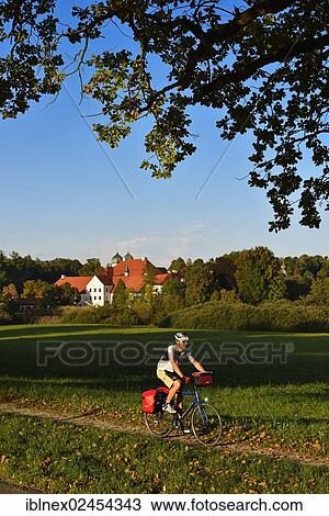 Stock Image - "Cyclist in front of Kloster Seeon, Seeon Monastery, Chiemgau, Bavaria, Germany, Europe". Fotosearch