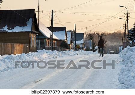 "Cyclist on snow-covered road, traditional wooden houses and piles of cleared snow, Bialowieza Village, Podlaskie Voivodeship, Poland, Europe" View Large Photo Image Stock Photo - "Cyclist on snow-covered road, traditional wooden houses and piles of cleared snow, Bialowieza Village, Podlaskie Voivodeship, Poland, Europe". Fotosearch