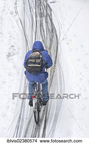 Picture - "Cyclist riding a bike in the snow, Stockholm, Sweden, Europe". Fotosearch