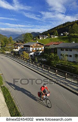 Stock Image - "Cyclist riding on a road, Ramsau, Berchtesgaden, Upper Bavaria, Bavaria, Germany, Europe". Fotosearch
