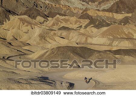 "Cyclist riding on the road through the badlands of the """"Twenty Mule Team Canyon"""" in the morning light, Death Valley, Death Valley National Park, California, USA" View Large Photo Image Stock Photo - "Cyclist riding on the road through the badlands of the """"Twenty Mule Team Canyon"""" in the morning light, Death Valley, Death Valley National Park, California, USA". Fotosearch