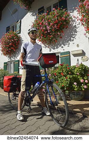 Picture - "Cyclists in front of a farmhouse, Schoenram Brewery, Chiemgau, Upper Bavaria, Bavaria, Germany, Europe". Fotosearch