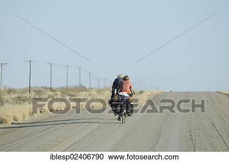 Stock Image - "Cyclists on a dusty track, Karas Region, Namibia, Africa". Fotosearch