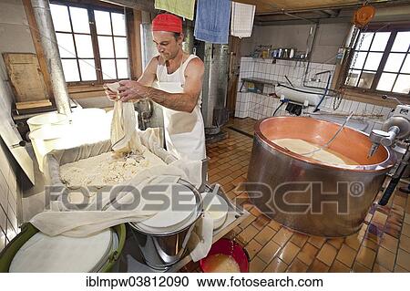 Stock Image - "Dairyman pouring the cottage cheese into a form, Alp Gun, Graubunden, Switzerland, Europe". Fotosearch