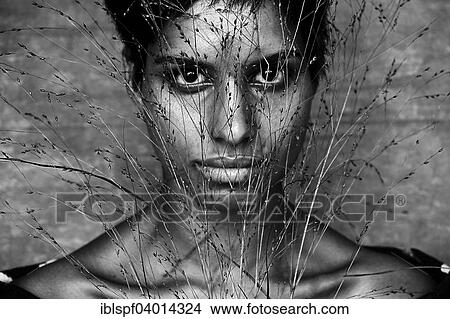 Picture - Dark-skinned woman behind blades of grass. Fotosearch