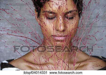 Dark-skinned woman with closed eyes behind red blades of grass View Large Photo Image Stock Image - Dark-skinned woman with closed eyes behind red blades of grass. Fotosearch
