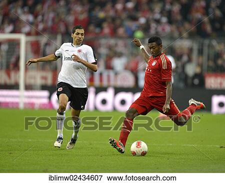 Stock Photo - "David Alaba, FC Bayern Munich, right, kicking the ball a, and Karim Matmour, Eintracht Frankfurt, left, Allianz Arena, Munich, Bavaria, Germany, Europe". Fotosearch