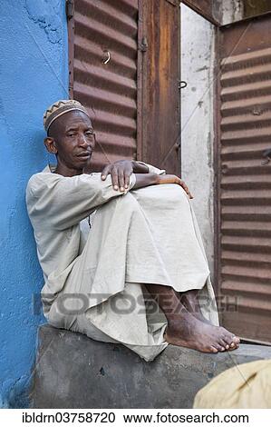 Stock Image - "Dealer sitting outside his shop, at a street market, Bo, Southern Province, Sierra Leone, Africa". Fotosearch