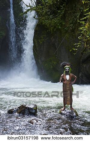 Stock Photo - "Decorated and painted tribal chief standing in front of a waterfall in the Highlands, Paya, Highland, Papua New Guinea, Oceania". Fotosearch