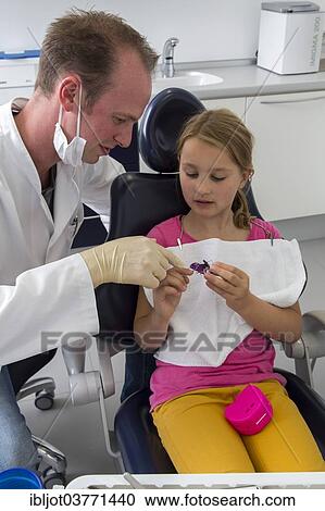 "Dentist discussing further treatment with a girl and showing her braces, Germany, Europe" View Large Photo Image Stock Image - "Dentist discussing further treatment with a girl and showing her braces, Germany, Europe". Fotosearch