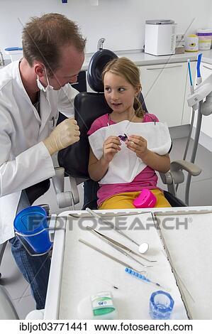 "Dentist discussing further treatment with a girl and showing her braces, Germany, Europe" View Large Photo Image Stock Image - "Dentist discussing further treatment with a girl and showing her braces, Germany, Europe". Fotosearch