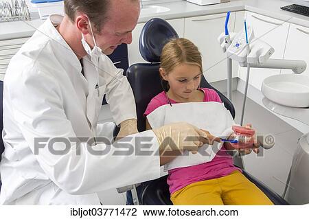 "Dentist showing a girl the proper use of a toothbrush, Germany, Europe" View Large Photo Image Stock Image - "Dentist showing a girl the proper use of a toothbrush, Germany, Europe". Fotosearch