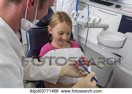 Stock Photograph - "Dentist showing a girl the proper use of a toothbrush, Germany, Europe". Fotosearch