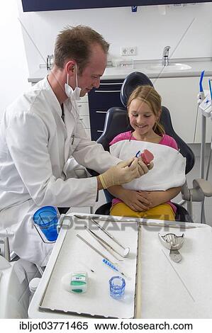 Stock Photography - "Dentist showing a girl the proper use of a toothbrush, Germany, Europe". Fotosearch