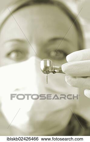 Stock Photograph - Dentist wearing a face mask and holding a drill. Fotosearch