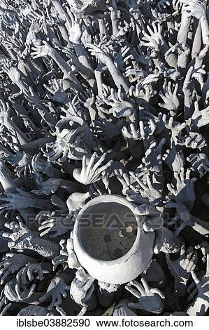 Stock Image - "Depiction of hell, hands pleading for help and a begging bowl, at Wat Rong Khun, bridge to the entrance of the White Temple, by architect Chalermchai Kositpipat, Chiang Rai, Chiang Rai Province, Northern Thailand, Thailand, Asia". Fotosearch