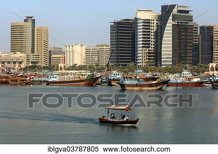 Stock Photography - "Dhows, traditional ships in the port at Dubai Creek in front of modern skyscrapers, Dubai, United Arab Emirates, Asia". Fotosearch