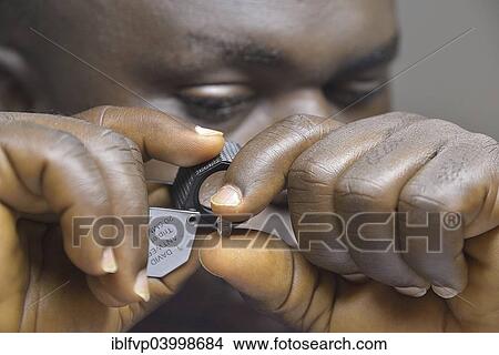 "Diamond dealer looking at a diamond through a magnifying glass, Koidu, Koidu-Sefadu, Kono District, Eastern Province, Sierra Leone, Africa" View Large Photo Image Picture - "Diamond dealer looking at a diamond through a magnifying glass, Koidu, Koidu-Sefadu, Kono District, Eastern Province, Sierra Leone, Africa". Fotosearch