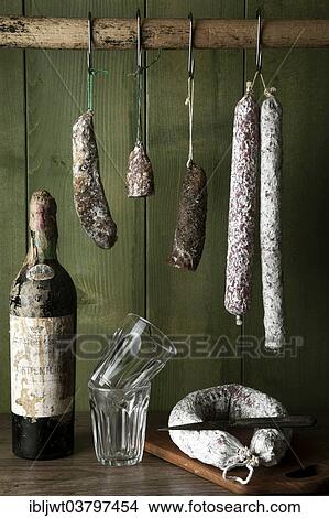 Different varieties of salami sausages hanging in front of a green wooden wall View Large Photo Image Picture - Different varieties of salami sausages hanging in front of a green wooden wall. Fotosearch