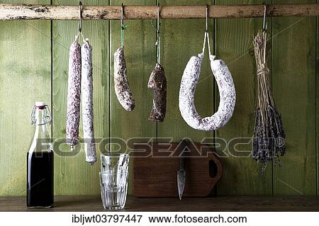 Different varieties of salami sausages hanging in front of a green wooden wall View Large Photo Image Stock Photo - Different varieties of salami sausages hanging in front of a green wooden wall. Fotosearch