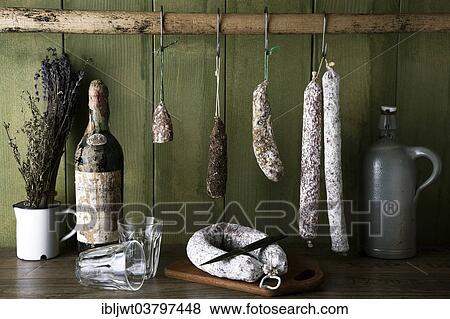 Different varieties of salami sausages hanging in front of a green wooden wall View Large Photo Image Stock Photo - Different varieties of salami sausages hanging in front of a green wooden wall. Fotosearch