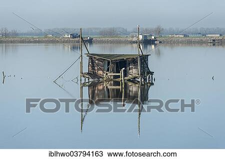 "Dilapidated fishing hut in a lagoon, with reflections, Po River Delta, Comacchio, Emilia-Romagna, Italy, Europe" View Large Photo Image Stock Image - "Dilapidated fishing hut in a lagoon, with reflections, Po River Delta, Comacchio, Emilia-Romagna, Italy, Europe". Fotosearch