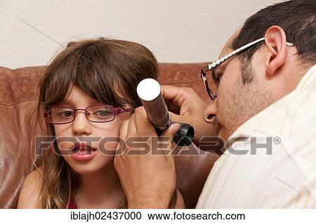 Doctor during a home visit examining a girl with an otoscope View Large Photo Image Stock Image - Doctor during a home visit examining a girl with an otoscope. Fotosearch