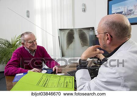 Stock Image - "Doctor's office, doctor talking to an elderly patient about the x-ray image of a lung, Germany, Europe". Fotosearch