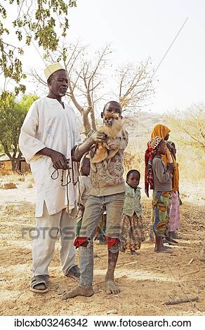 Stock Image - "Doro, 73, chief of the homestead, with his grandchildren and a monkey, Bogdi, Garoua, North Region, Cameroon, Africa". Fotosearch