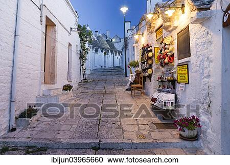 Stock Image - "Dusk, shop, trulli traditional round houses, Rione Monti, Alberobello, Valle d'Itria, Trulli Valley, Apulia, Italy, Europe". Fotosearch