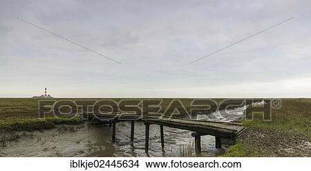 Picture - "Dwelling mound, jetty, Westerheversand, the lighthouse at the back, Eiderstedt, Northern Friesland, Schleswig-Holstein, Germany, Europe". Fotosearch