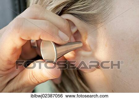Stock Photograph - "Ear, nose and throat specialist examining a girl with an ear speculum". Fotosearch